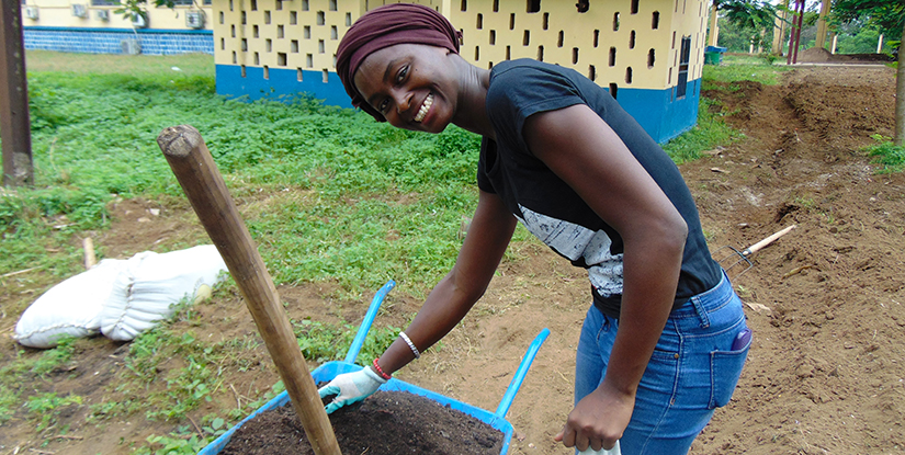 young woman digging with wheelbarrow