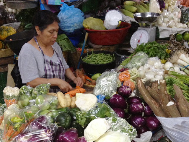 Woman chopping and weighing vegetables in a market in Guatemala