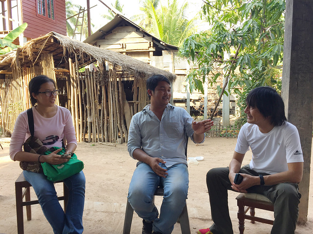 Three people sit talking outdoors