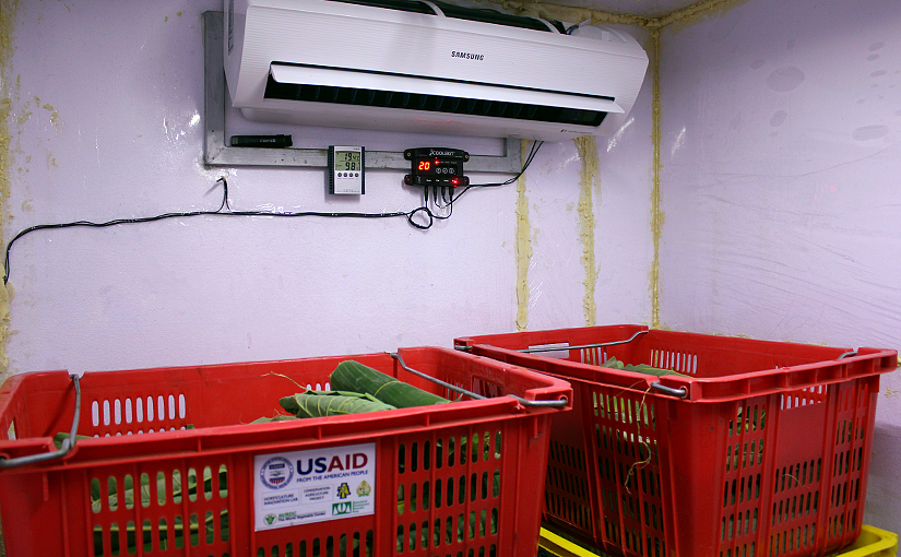 Photo of the coolbot hooked up to an air conditioner above produce crates