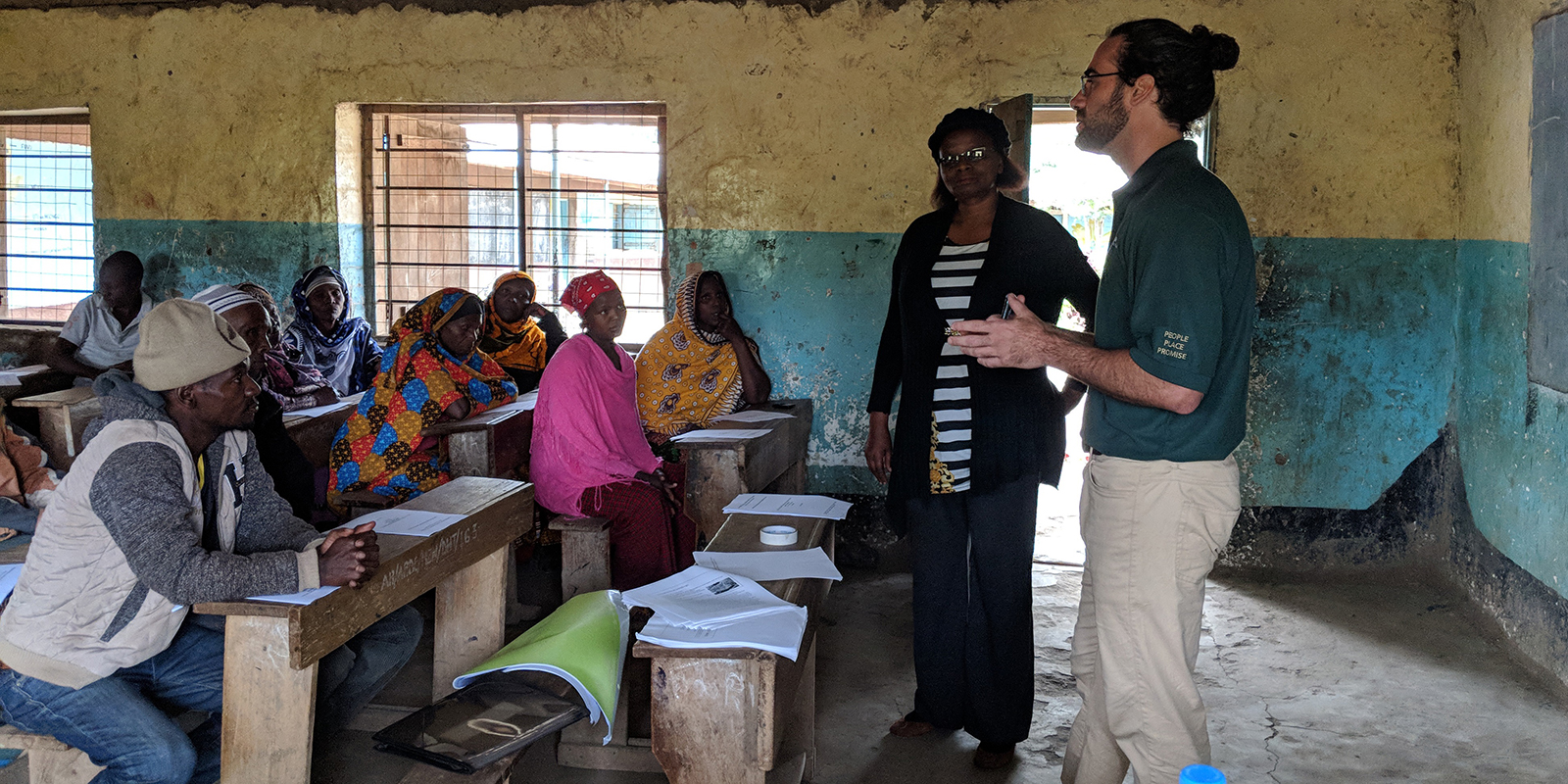 UH Manoa student with local extension agent at front of classroom full of farmers and agricultural professionals in Tanzania