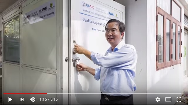 Poonpipope "Poon" Kasemsap opens door to cold room with USAID Hortiulture Innovation Lab logos on it