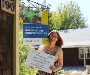 Amanda Crump, associate director, hangs a new office sign as the program adjusts to its new name, the Horticulture Innovation Lab