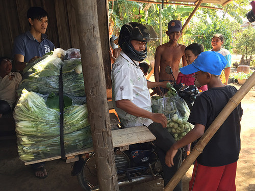 A man prepared to pull out astride a motorbike piled with bagged vegetables