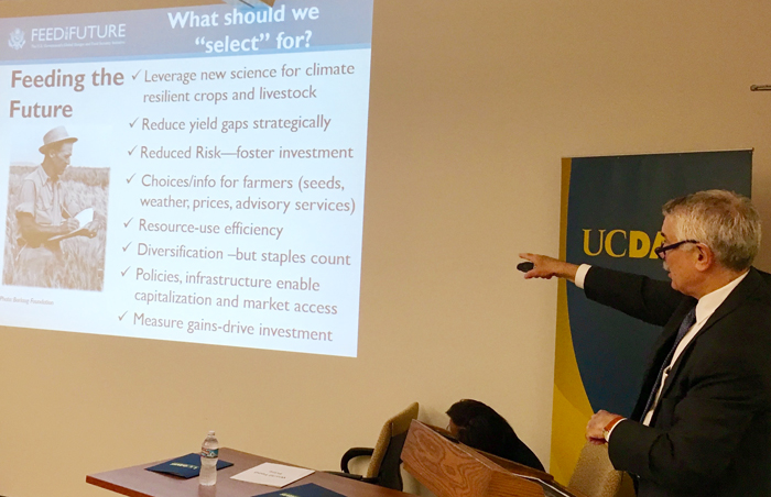 Bertram pointing at Feed the Future powerpoint slide with UC Davis banner in background