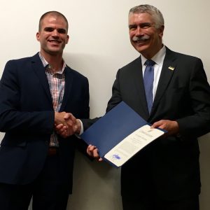 March and Bertram shaking hands with certificate