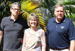 Group photo, three people in front of palms