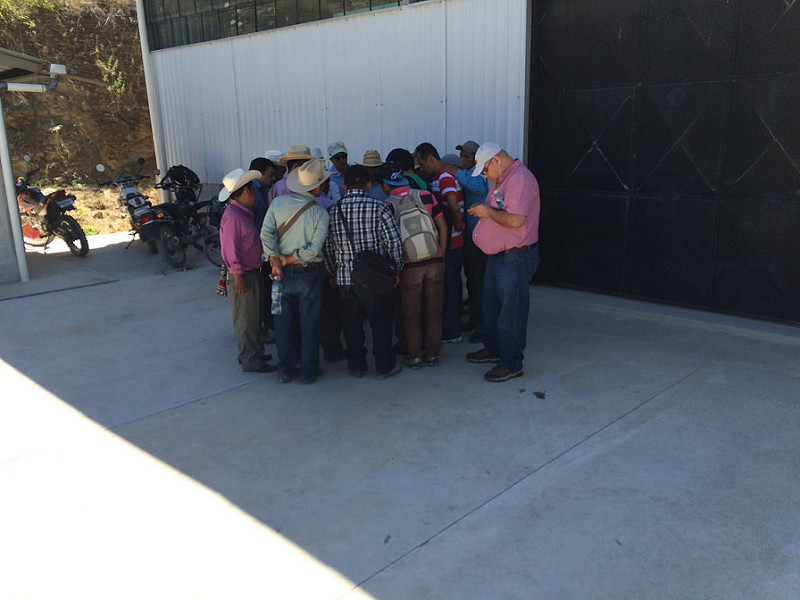 Group huddles together, outside in the shade of a building