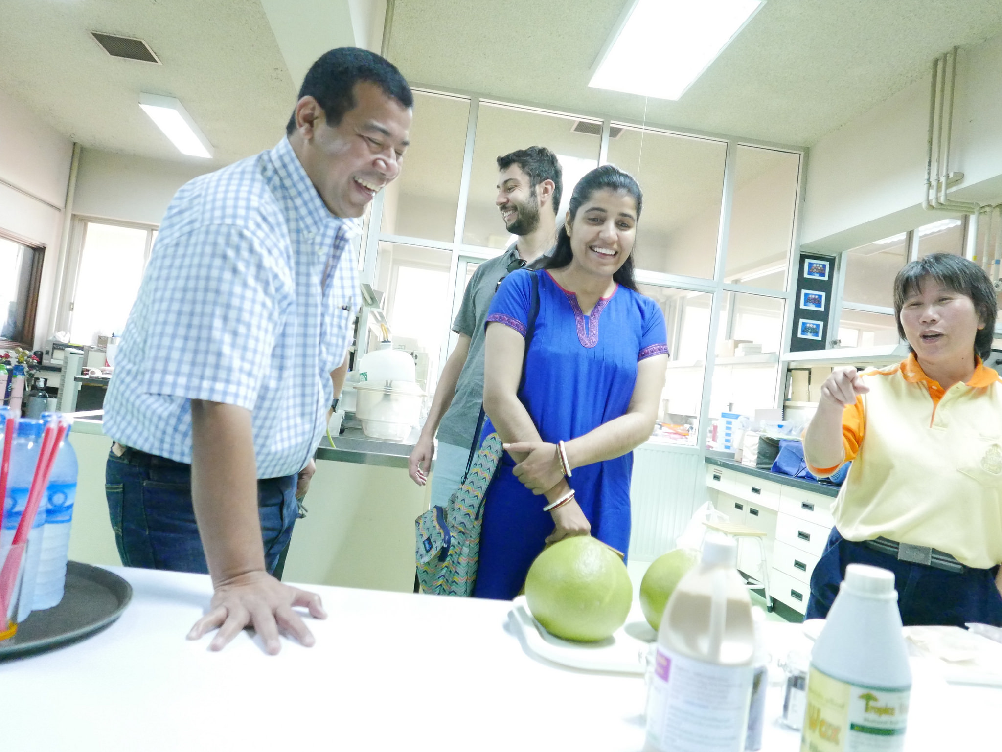 Four people stand in a lab looking at produce, talking