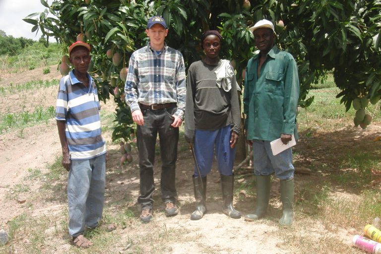 student and farmers in front of mango tree