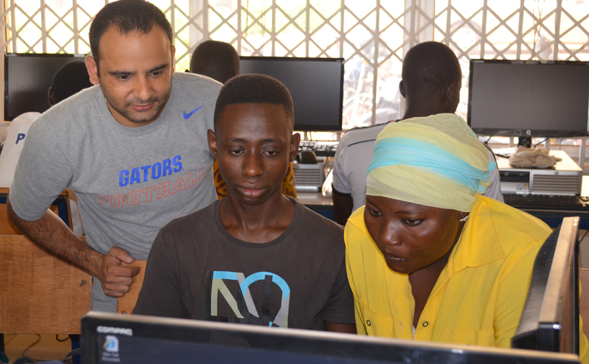 student in Florida shirt works with two students from Ghana at a computer screen