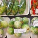 Fresh vegetables sit on Styrofoam trays covered in cling wrap with labels